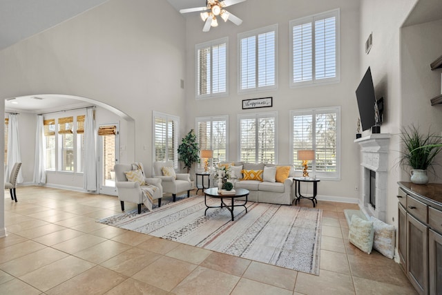 living area with arched walkways, light tile patterned flooring, a fireplace, visible vents, and baseboards