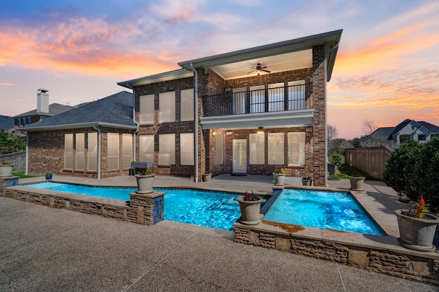 back of property featuring a balcony, a patio area, fence, and brick siding