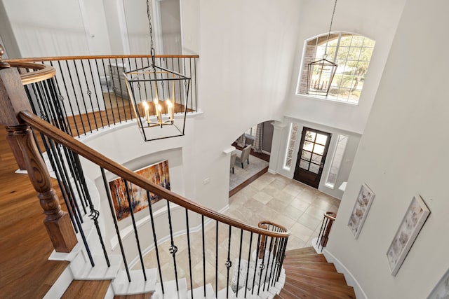 foyer featuring arched walkways, baseboards, a high ceiling, and an inviting chandelier