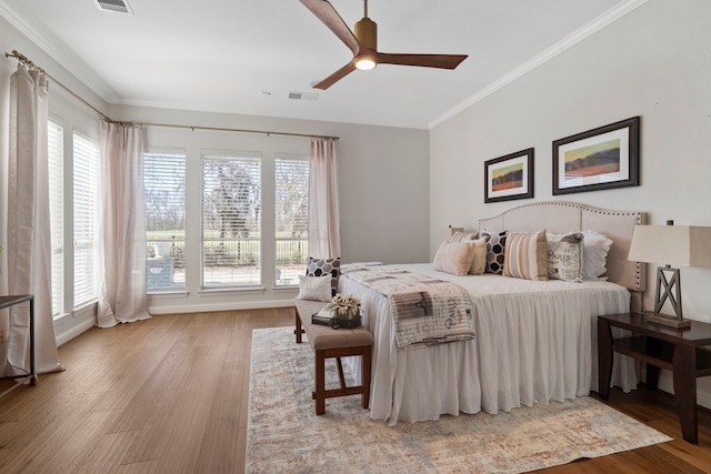 bedroom with a ceiling fan, light wood-style flooring, visible vents, and crown molding