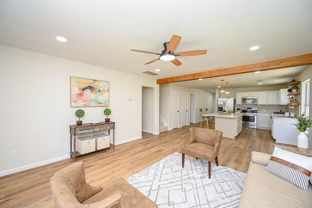 living area featuring visible vents, light wood finished floors, baseboards, recessed lighting, and stairs