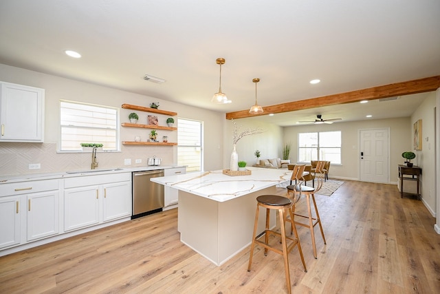 kitchen with tasteful backsplash, visible vents, open floor plan, stainless steel dishwasher, and a sink