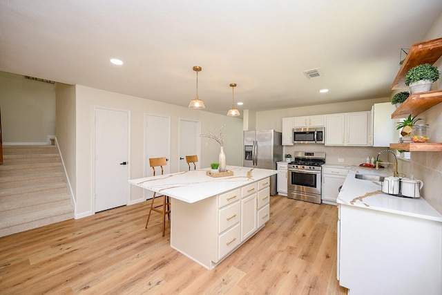 kitchen with visible vents, a sink, open shelves, appliances with stainless steel finishes, and light wood finished floors