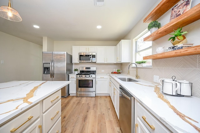 kitchen with a sink, open shelves, backsplash, white cabinetry, and appliances with stainless steel finishes