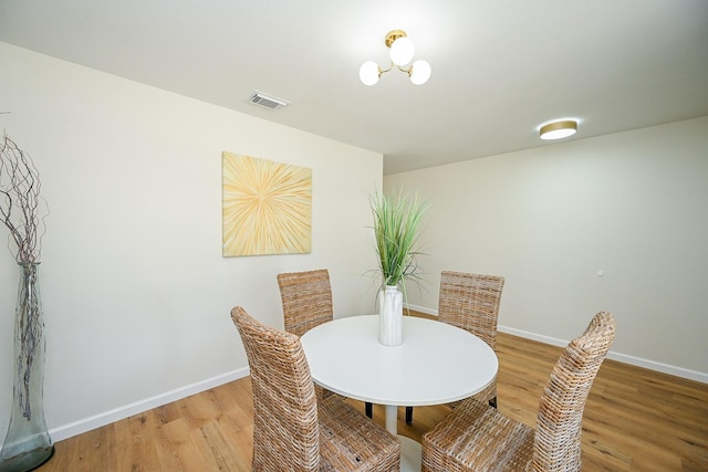 dining area with light wood-style floors, visible vents, and baseboards