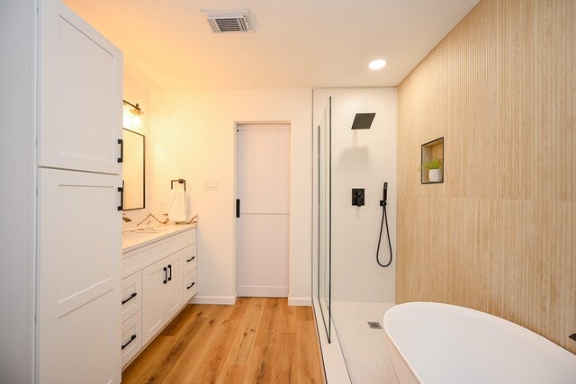 full bathroom with vanity, wood finished floors, visible vents, tiled shower, and a freestanding tub