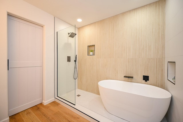 full bathroom with a soaking tub, recessed lighting, wood finished floors, and a tile shower