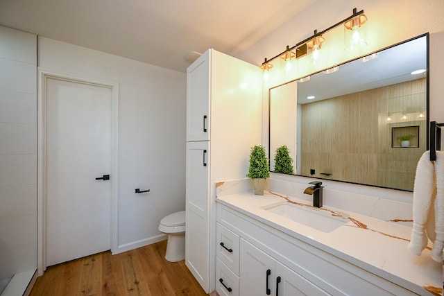 bathroom with toilet, wood finished floors, and vanity