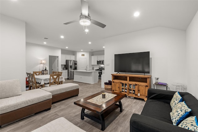 living area with light wood-style flooring, vaulted ceiling, a ceiling fan, and recessed lighting