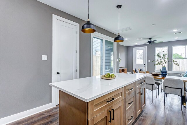 kitchen featuring baseboards, dark wood finished floors, open floor plan, a center island, and decorative light fixtures