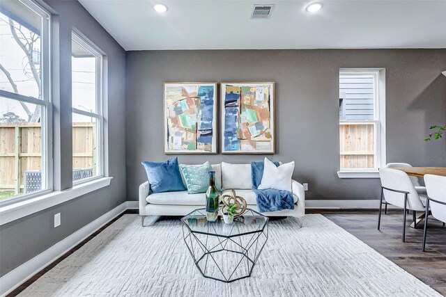 living room with visible vents, plenty of natural light, baseboards, and wood finished floors