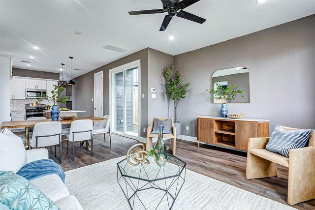 living room featuring visible vents, baseboards, wood finished floors, and recessed lighting