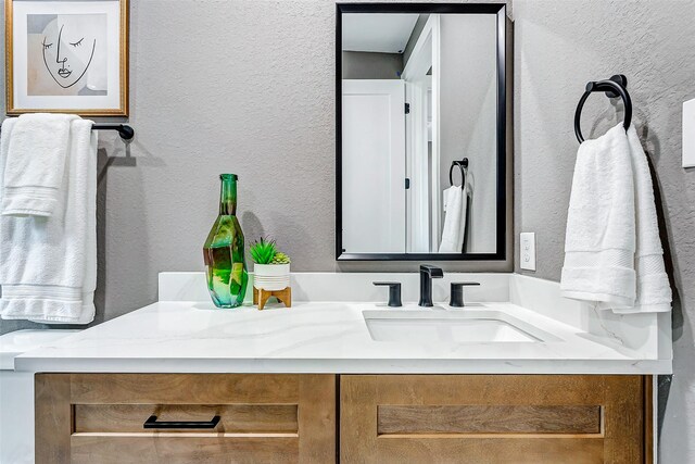 bathroom with a textured wall and vanity