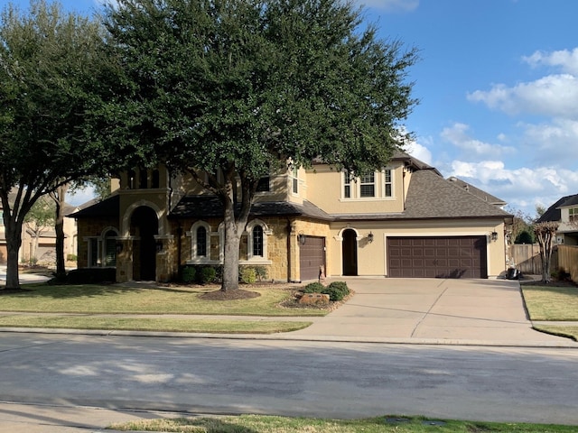 view of front of house with driveway, stucco siding, fence, and a front yard