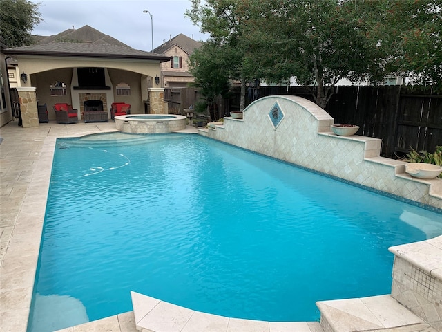 view of pool featuring a pool with connected hot tub, a patio area, a fenced backyard, and exterior fireplace