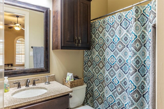 bathroom with toilet, vanity, a shower with shower curtain, and a ceiling fan