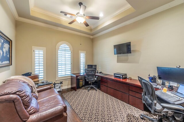 office featuring a ceiling fan, a tray ceiling, crown molding, and dark wood-style flooring