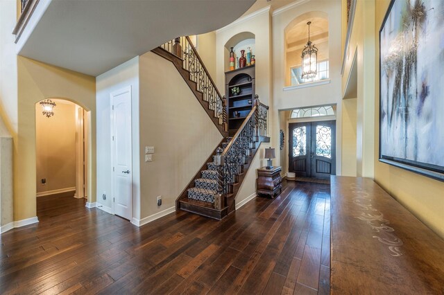 foyer entrance featuring stairway, baseboards, a notable chandelier, and hardwood / wood-style floors