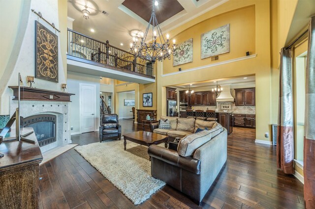 living room with an inviting chandelier, dark wood-type flooring, coffered ceiling, and a tile fireplace