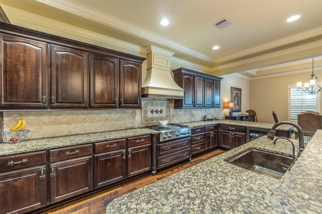 kitchen with premium range hood, visible vents, a sink, stainless steel gas stovetop, and light stone countertops