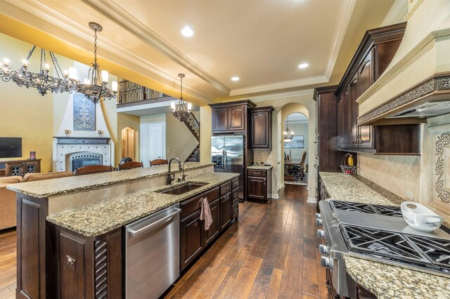 kitchen with premium range hood, arched walkways, a sink, appliances with stainless steel finishes, and a raised ceiling