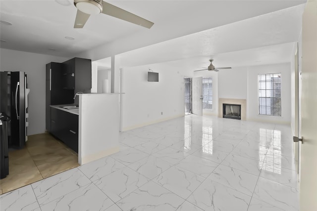 living area featuring marble finish floor, a fireplace, ceiling fan, and baseboards