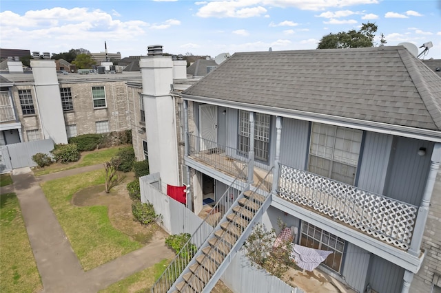 exterior space featuring roof with shingles, fence, and a chimney