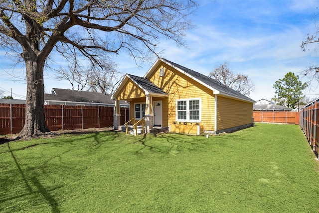 rear view of property featuring a lawn and a fenced backyard