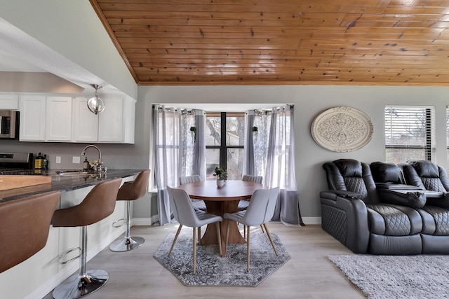 dining room featuring light wood-type flooring, wooden ceiling, vaulted ceiling, and a wealth of natural light