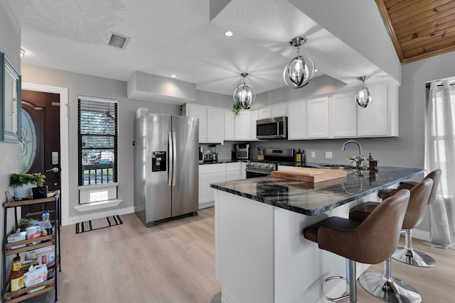 kitchen featuring stainless steel appliances, a peninsula, a sink, visible vents, and white cabinetry