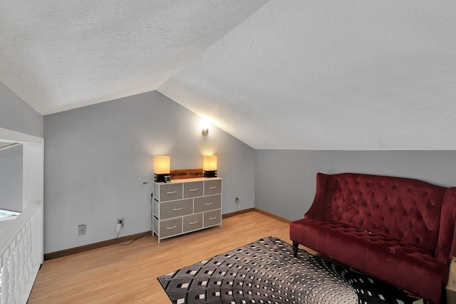 living area featuring baseboards, vaulted ceiling, a textured ceiling, and light wood finished floors