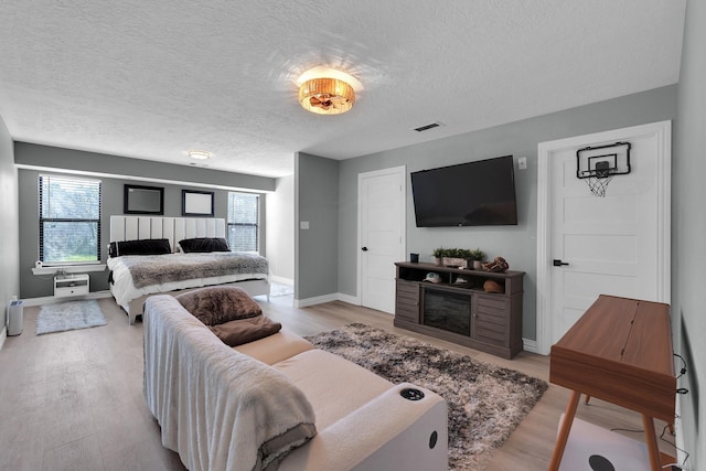 living room featuring baseboards, a fireplace, visible vents, and light wood finished floors