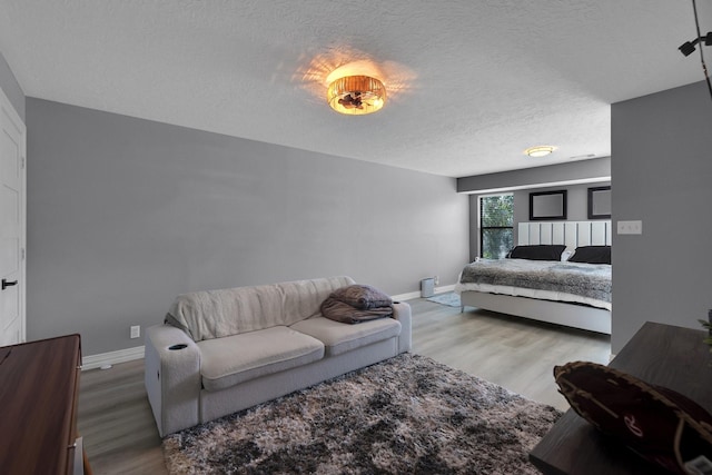 bedroom featuring a textured ceiling, wood finished floors, and baseboards