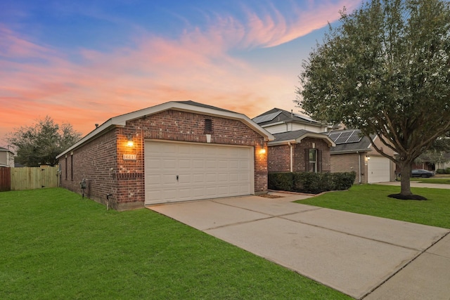 view of front of house with brick siding, concrete driveway, a lawn, fence, and a garage