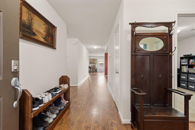 hallway with wood-type flooring, visible vents, and baseboards