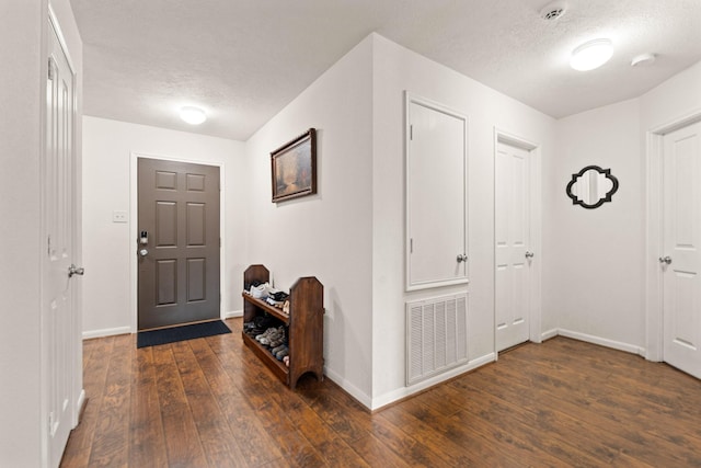 foyer entrance with baseboards, a textured ceiling, visible vents, and dark wood-style flooring