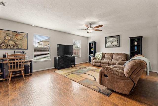 living area with visible vents, baseboards, a ceiling fan, wood finished floors, and a textured ceiling