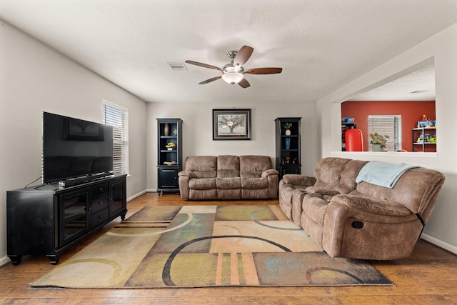 living room featuring baseboards, wood finished floors, visible vents, and a ceiling fan