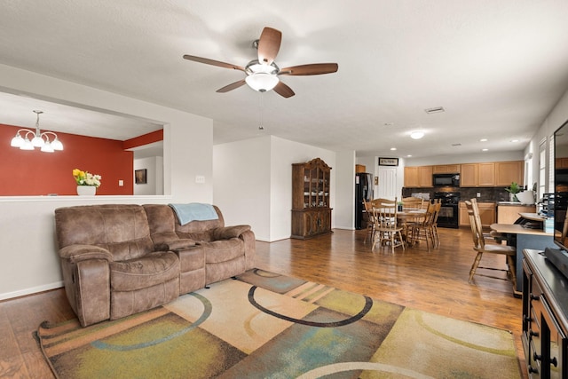 living area featuring dark wood-style floors, ceiling fan with notable chandelier, baseboards, and recessed lighting