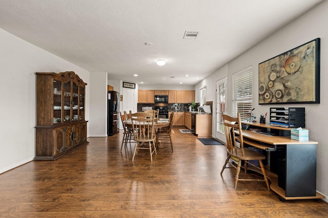 dining space with a textured ceiling, dark wood finished floors, visible vents, and baseboards