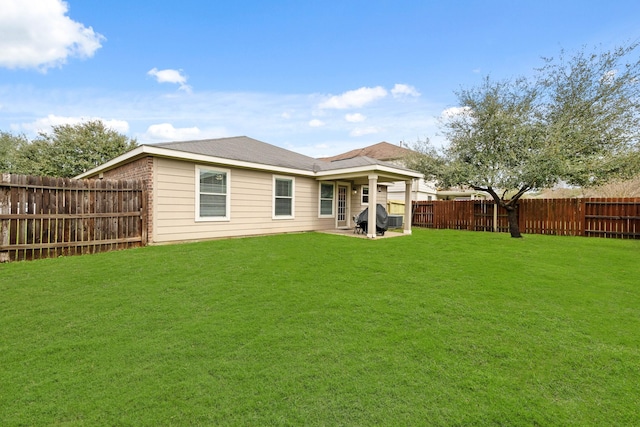 back of property with a patio area, a fenced backyard, roof with shingles, and a yard