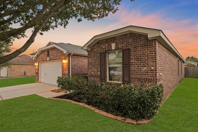 view of front of home with an attached garage, brick siding, fence, driveway, and a lawn