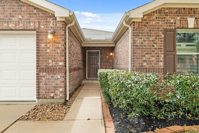 view of exterior entry featuring brick siding and an attached garage