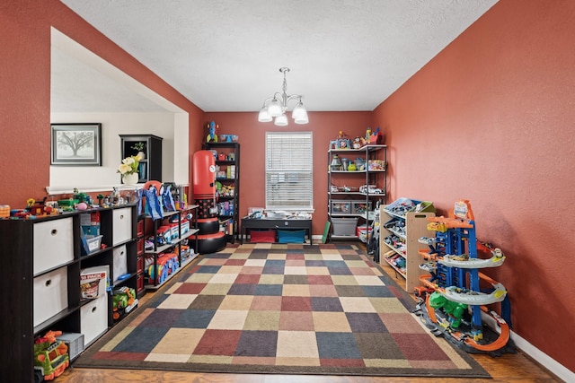 playroom with a textured ceiling, baseboards, and an inviting chandelier