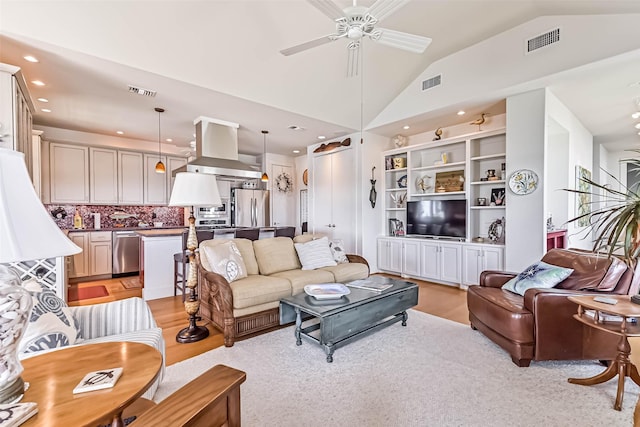 living area featuring visible vents, vaulted ceiling, and ceiling fan