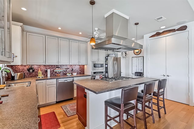 kitchen featuring light wood finished floors, visible vents, appliances with stainless steel finishes, island exhaust hood, and a sink