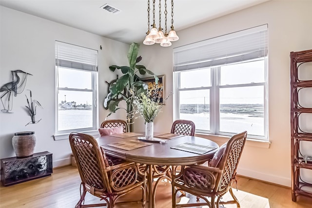 dining room featuring baseboards, visible vents, light wood finished floors, and an inviting chandelier