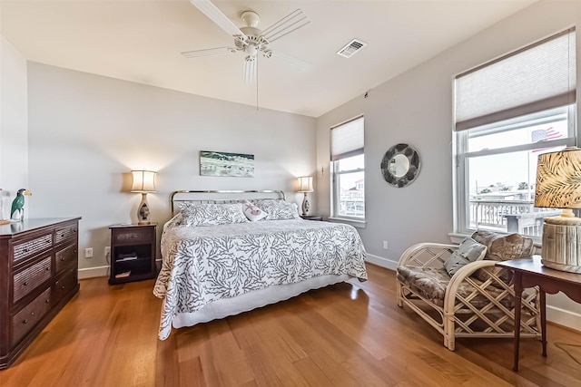 bedroom featuring baseboards, visible vents, ceiling fan, and wood finished floors