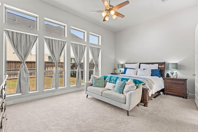 carpeted bedroom featuring multiple windows, a ceiling fan, and baseboards