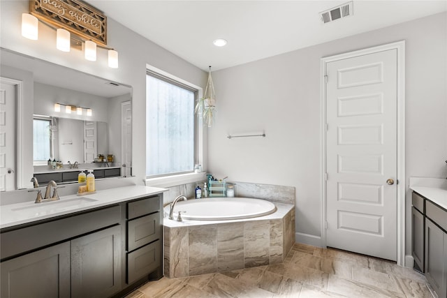 bathroom with vanity, a garden tub, and visible vents